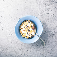 Healthy food background with homemade oatmeal granola or muesli with yogurt for healthy morning breakfast, top view, copy space. Toned photo.