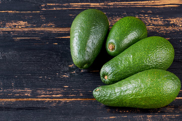 Fresh avocados on the dark wooden background with free copy space. Raw ingredients for veggie salad or diet dish. Side view