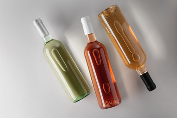 Bottles with different kinds of wine on grey background