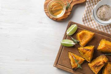 Tasty baked pumpkin pieces and honey on white table