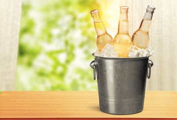 Beer bottles in ice on beach background