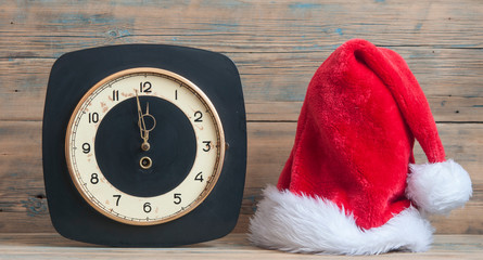 vintage wall clock with Santa hat on wooden table