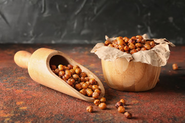 Bowl and scoop with fried chickpeas on color table