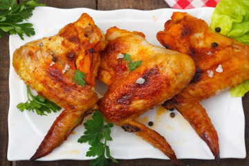 Close up of homemade, grilled chicken wings on white plate, top view