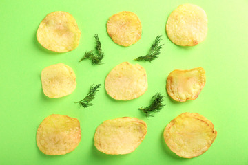 Tasty potato chips with dill on color background