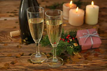 Glasses of champagne with burning candles on wooden table