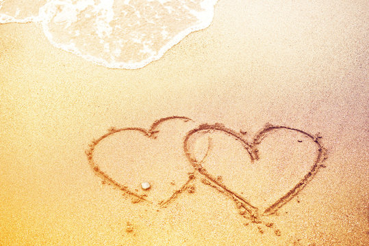 Drawing of heart and sea wave on sand on the seashore, toned. Bright background by St. Valentine's Day, the romantic image