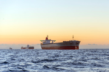 huge ships at sea at sunset with orange sky bacjground