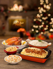 table with roasted chicken, bolognaise pasta, rice and mayonnaise with Christmas background