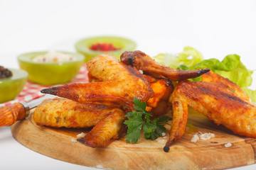 Homemade crispy, roasted chicken wings on wooden board, closeup, white background