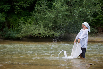 A girl in a long village vintage clothes standing in the river and washes clothes.