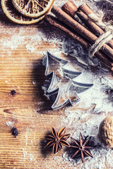 Top of view bakery table full of christmas aromatic ingredients star anise cinnamon dried orange flour cookery book and cookie cutters