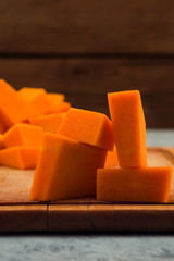 Slices of pumpkin on wooden background. Close up. Raw vegetables. Vegetarian food.