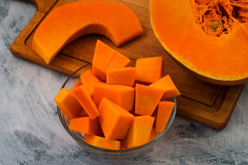 Cooking pumpkin. Cut into wedges and slices of orange flesh. Kitchen cutting Board. Light background. Raw vegetables. Vegetarian food.