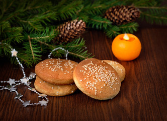 Christmas homemade cookies, fir branches, pine cones and a candle on a wooden background.
