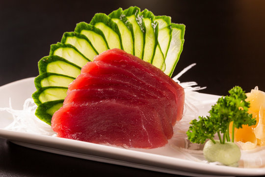 sashimi with tuna in a white plate. On a black background.