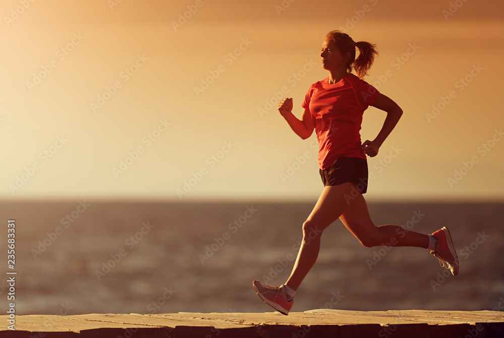 Wall mural Woman running on beach in morning sunrise, fitness workout sport