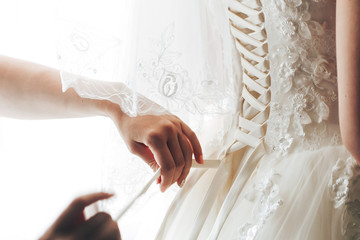 Wedding dress close-up. Lacing wedding dress. The bride is preparing for the wedding. Morning preparations. A woman wears a dress