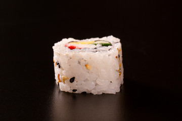Japanese cuisine. One peace of sushi roll isolated on black background Closeup shot