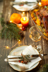 Festive table setting bowls and cutlery, glasses of wine against a background of baked duck