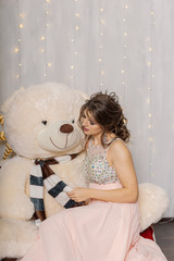 Very beautiful and sexy woman in a pink dress with a big bear in the New Year's decor, stealing in the New Year's style.