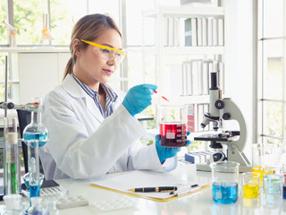 Fototapeta premium Asia scientific researcher holding a test tube of clear solution in a lab
