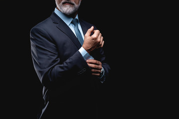 elegant mature fashion man looking at his cufflinks while fixing them.