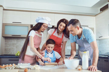 Obraz na płótnie Canvas A happy family prepares baking in the kitchen
