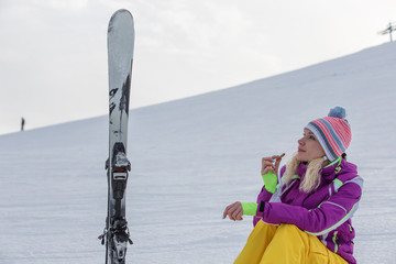 A young girl in a ski suit skis eating cookies in a snowy forest in winter