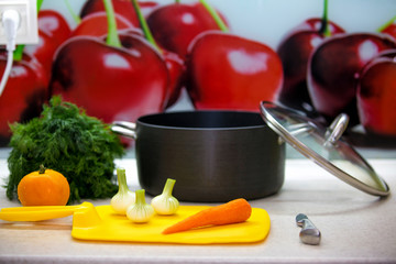 Vegetables for soup, knife, a yellow board and a pan lie on the kitchen table. Quail soup cooking process