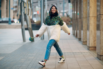 Young stylish woman in fur coat walking street