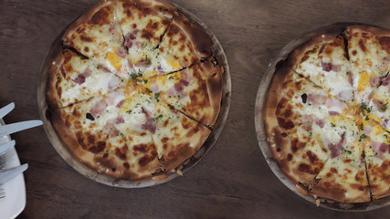 Cut into slices delicious fresh pizza  on a dark wooden table background. Top view.
