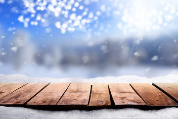 A wooden table top with a snowy white and blue Christmas scene with space for text and product shots.