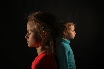two young girls with closed eyes on a black background