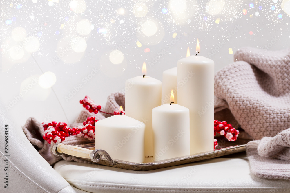 Canvas Prints four white burning advent candles with red berries and knitted blanket on chair with bokeh lights