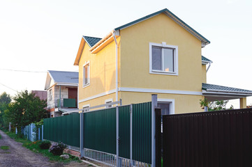 Two-storey private house behind an iron fence. Suburban housing.