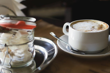 Cappuccino coffee in a cup and sugar refined in a cafe. Close-up, selective focus.
