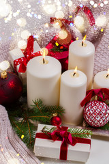 White glowing advent candles with christmas decorations and with bokeh lights