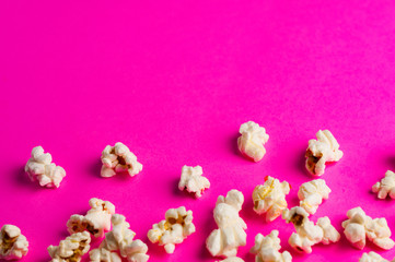 Scattered cooked popcorn on pink background with copy space. Сoncept of leisure