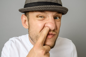 Man picking his nose on gray background