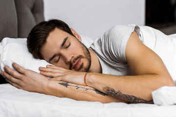 handsome bearded tattooed young man sleeping in bed