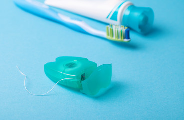 Dental floss and toothbrush on a blue background.