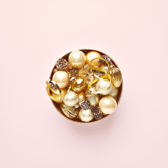 Golden Christmas decorations in a gift box on pink background. Flatlay