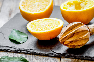cut oranges in half and juicer on wooden background