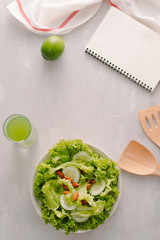Fresh salad with tomatoes, cucumbers and lettuce on a wooden background