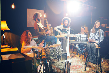 Band practice in home studio. Woman singing while rest of the band playing instruments.
