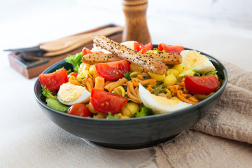 Salad of pasta, egg, smoked salmon tartare, salad and tomato, with a citrus vinaigrette sauce.