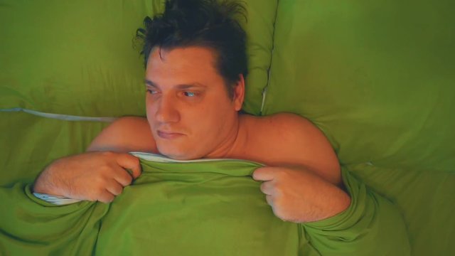funny faddish man hiding under his blanket lying in bed