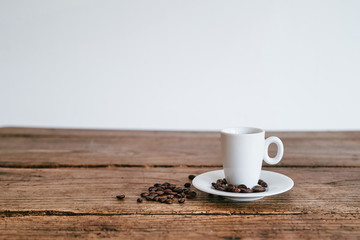 Espresso Tasse mit Kaffee Bohnen auf Unterteller Holztisch Hintergrund weiß