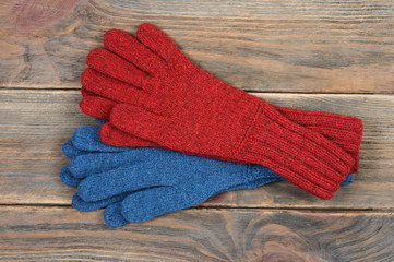 Knitted gloves in red and blue handmade. On a wooden background. View from above.